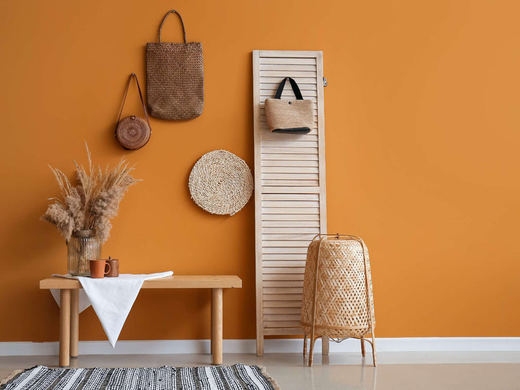 An orange-painted kitchen with a wall of white subway tile, white counters, and copper kitchen instruments.