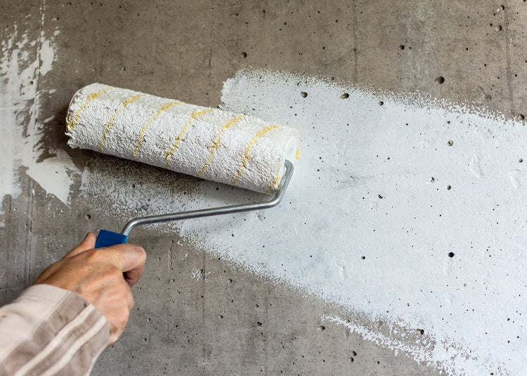 hand using paint brush with white primer on wall